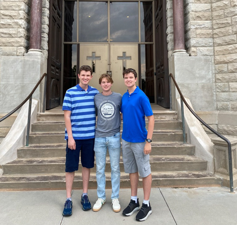 Adam Boblenz, center, pictured with two friends on the steps of St. John's Church.