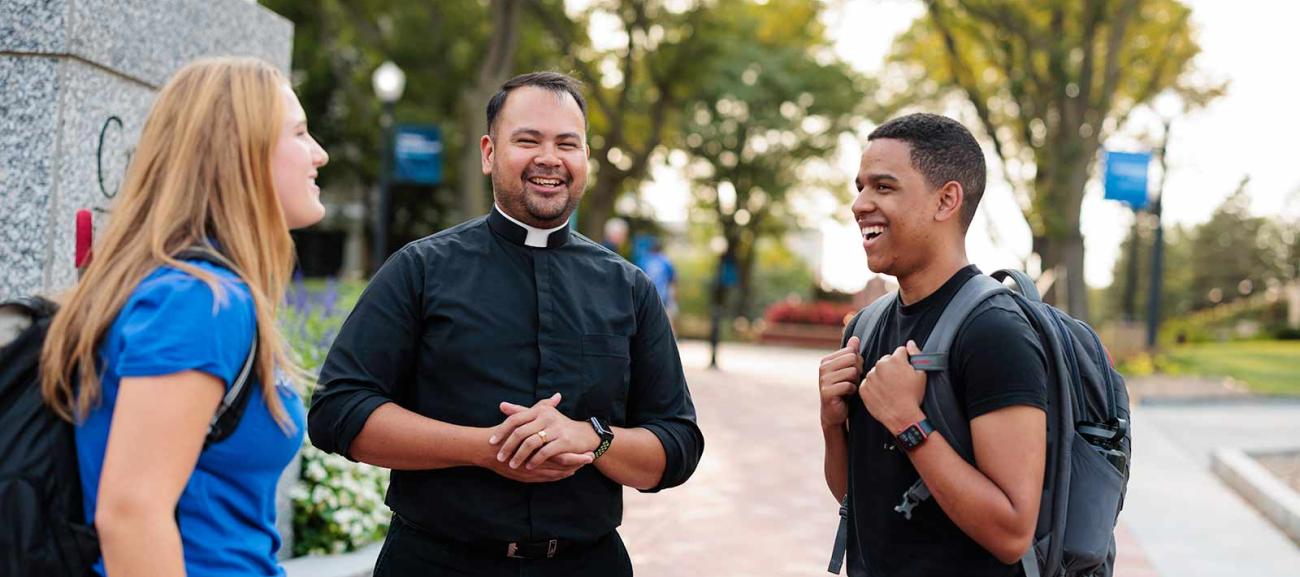 Two students speak with a Jesuit.