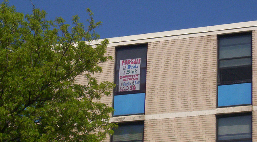 Image of sign outside dorm window that says "For sale, 2 beds, 1 sink, community bathroom, $6250"