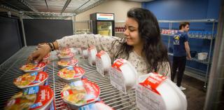 A student arranges food items at the Creighton Cupboard.