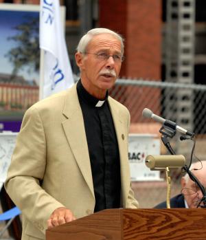A Jesuit speaks into a microphone