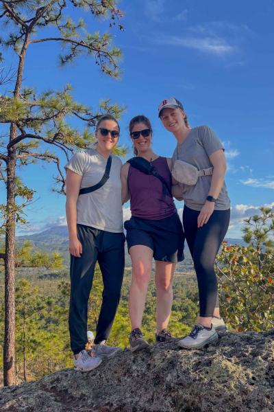 Three women pose for a photo while on a hike