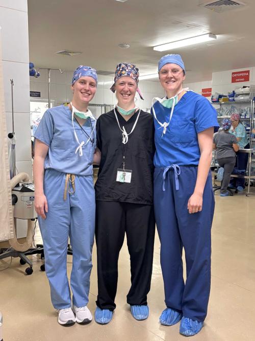Three women volunteering together pose for a photo in a hospital in Honduras