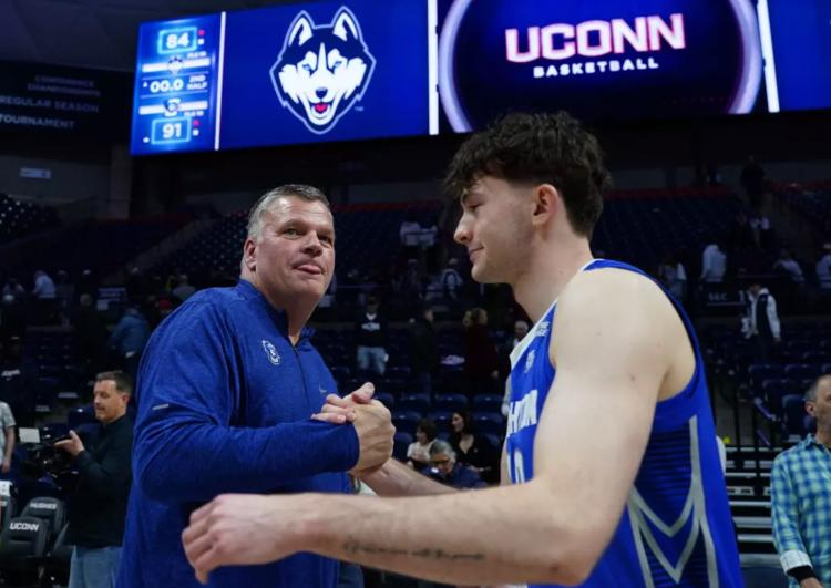 A basketball coach shakes hands with a player