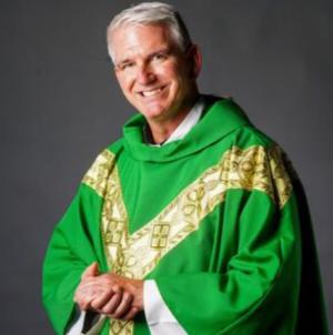 A priest smiles for a photo