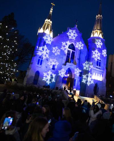 Students gather outside an illuminated church to see Christmas lights at night