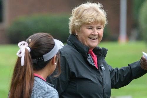 A smiling golf coach talks to one of her student athletes