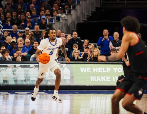 A basketball player dribbles the ball up the court