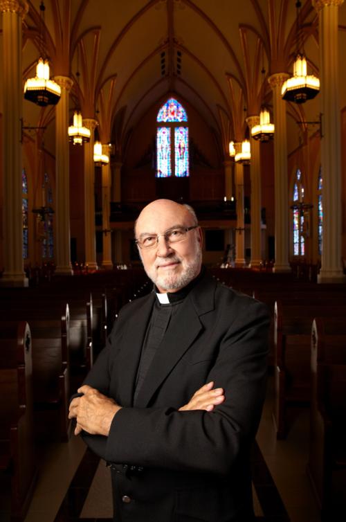 Richard Hauser stands with his arms crossed inside a church