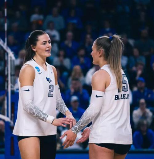 Two volleyball players talk after a rally
