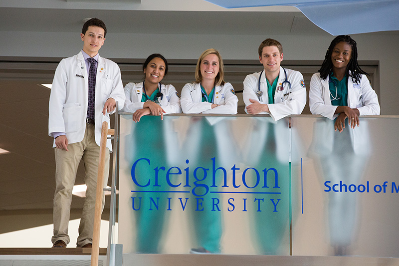 A group of medical students smile and pose for the camera.