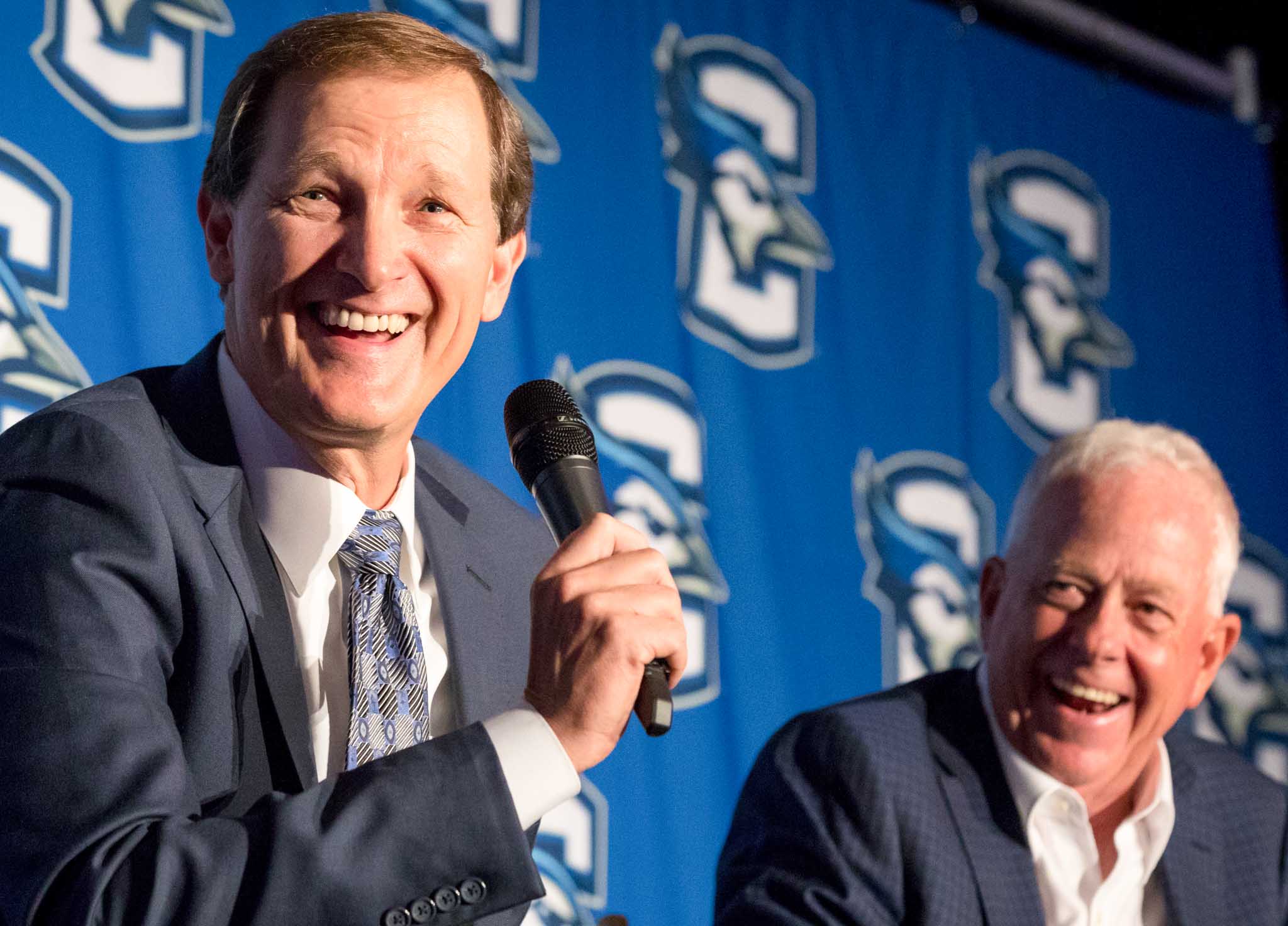 Two men smiling while speaking on a panel