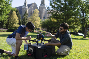 student and instructor working with a drone on Creighton campus