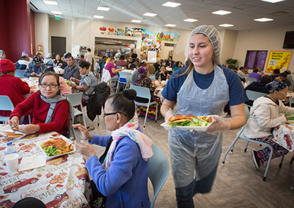 A student serves food at a community center