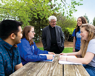 Jesuit and students talk in the Jesuit gardens