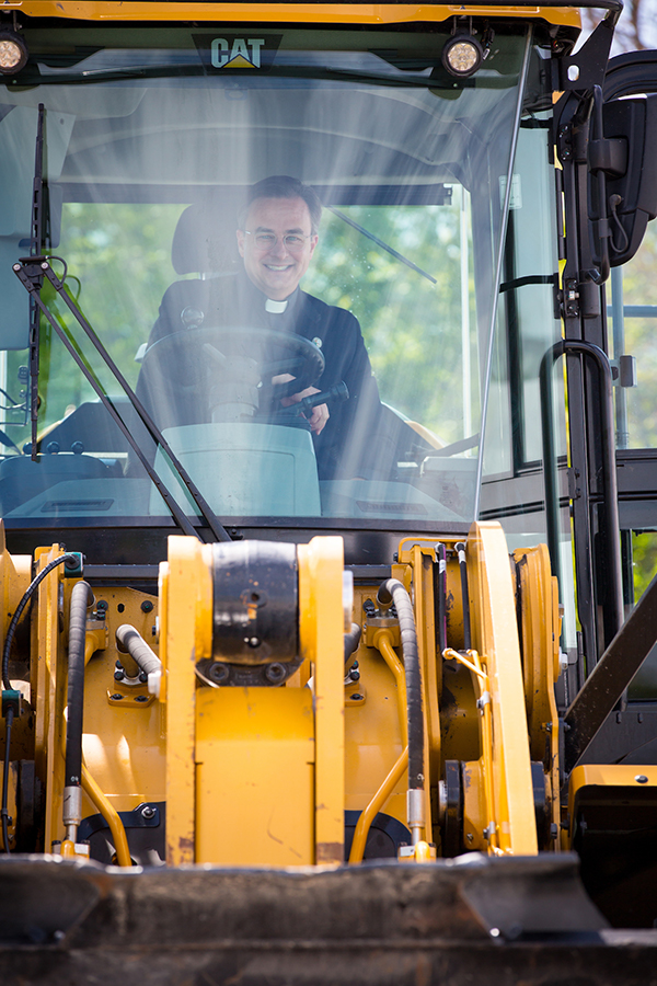 Father Hendrickson behind the wheel of the forklift at the groundbreaking.