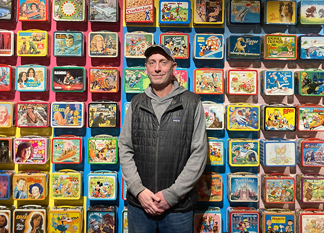 Mark Kelehan pictured in front of a bunch of lunchboxes at his Durham exhibit.