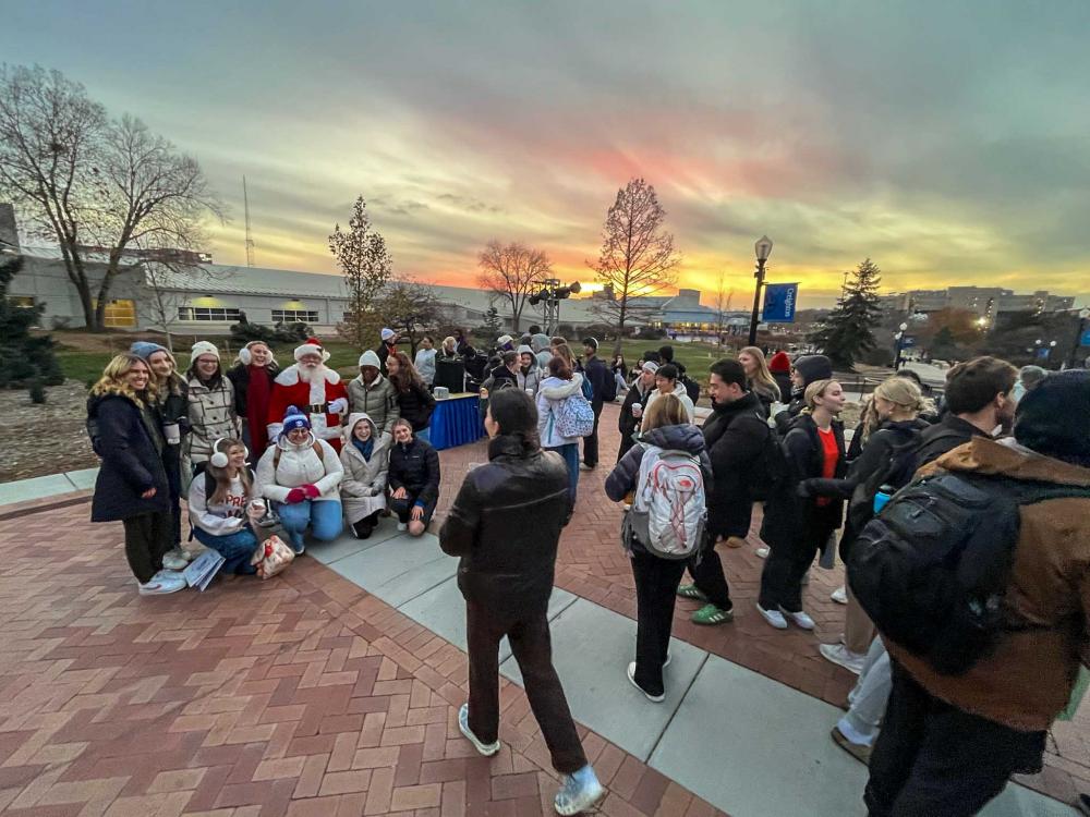 One student takes a photo while others pose with Santa Claus