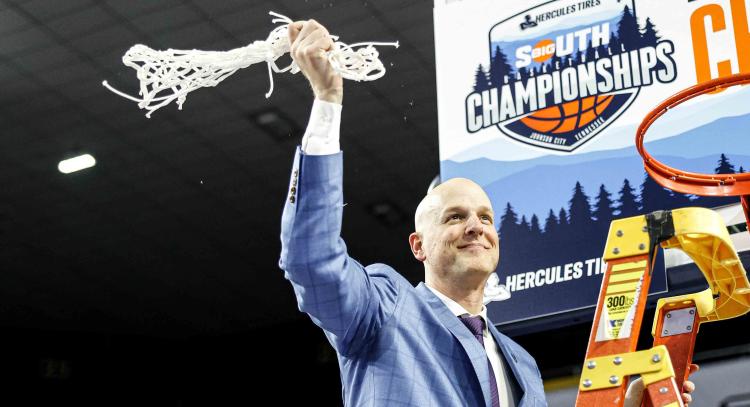 A basketball coach stands on a ladder and waves a net in the air