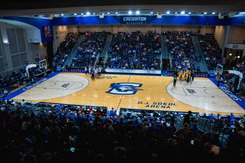 Two women's basketball teams huddle on the court before a full arena