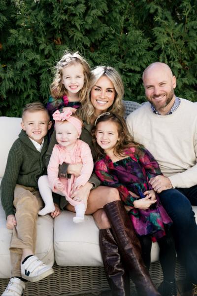 A family of five poses together on a couch for a photo