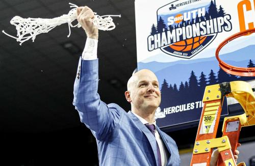 A coach stands on a ladder and waves a net