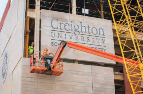 Construction crews install a sign on a building