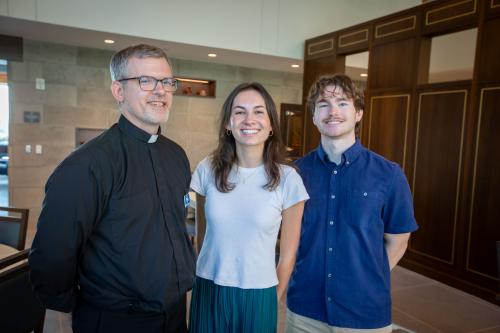 A Jesuit priest and two students smile together