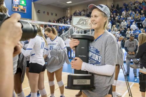 A volleyball player holds a championship trophy