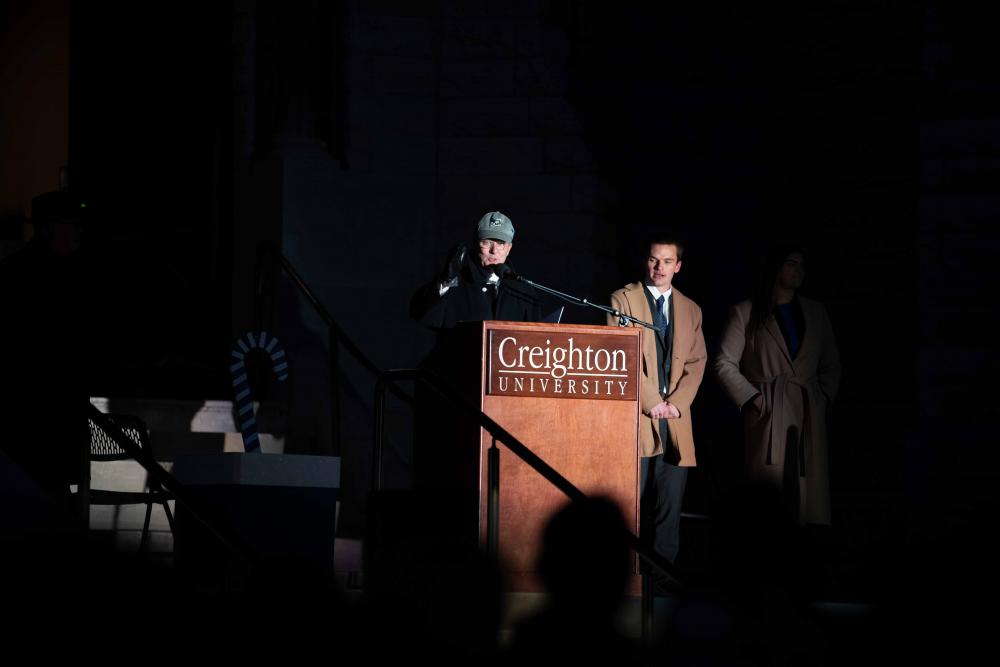 Creighton's president speaks behind a lectern at night