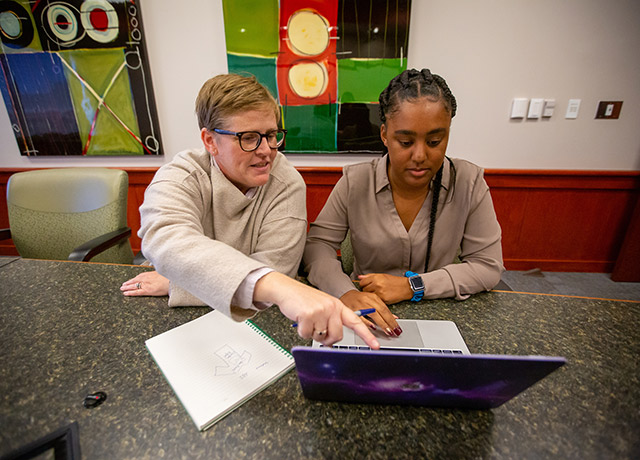 Joy Suder and Sidnea Brown look at a laptop screen.