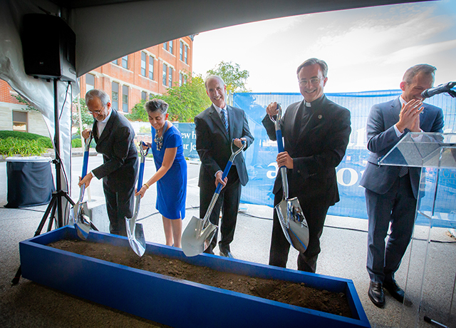 Donors and university leaders shovel dirt at the Jesuit Residence ceremonial groundbreaking.