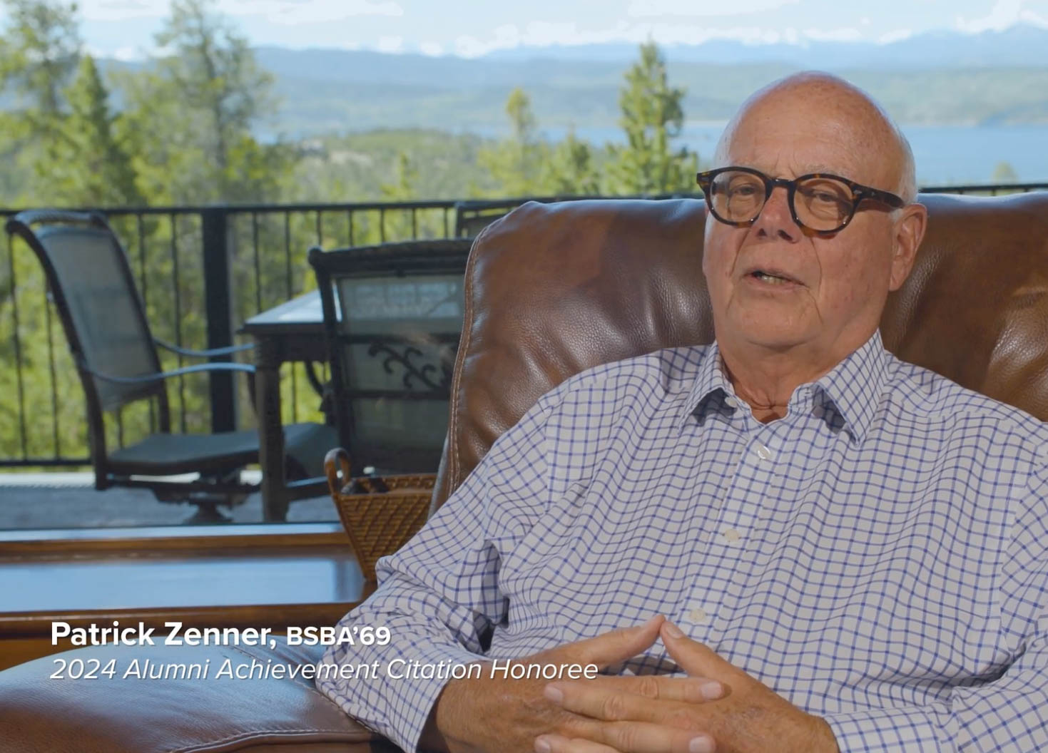 Patrick Zenner sits in a chair and speaks on camera with a scenic landscape behind him