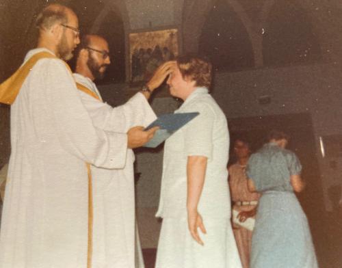 A priest touches the forehead of a female graduate