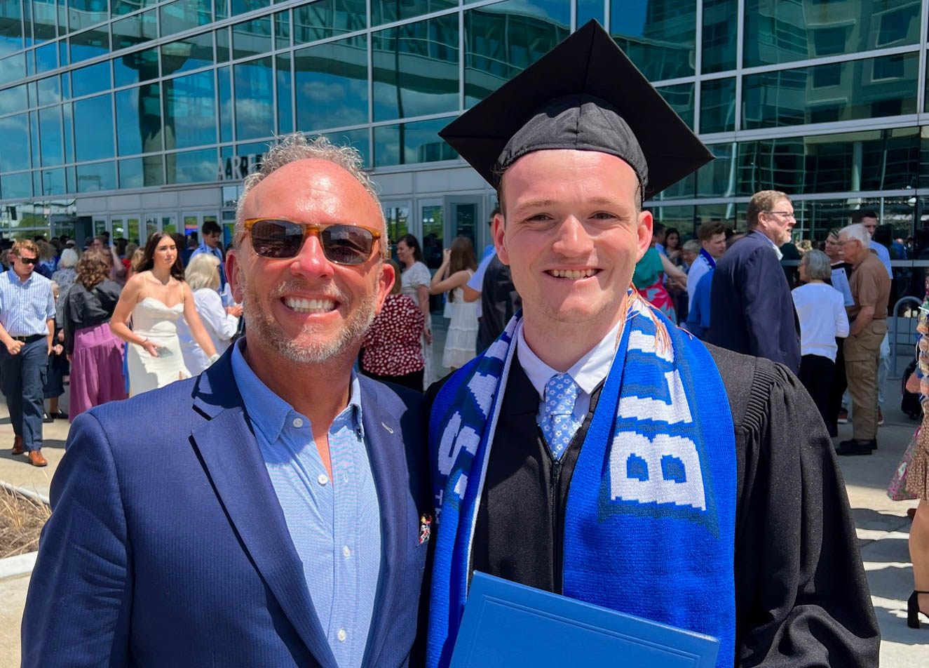 A dad and a son pose for a photo on graduation day