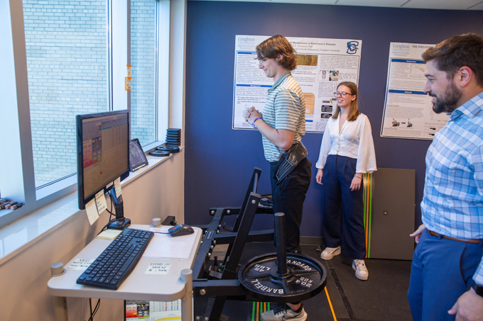 A student lifts while Stoffel and Magrini observe.