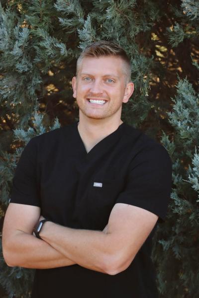 A smiling dentist in front of a tree