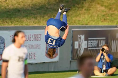 A soccer player flips in the air to celebrate