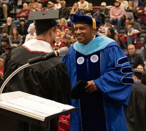 Ron Patterson shakes hands with a student at winter commencement