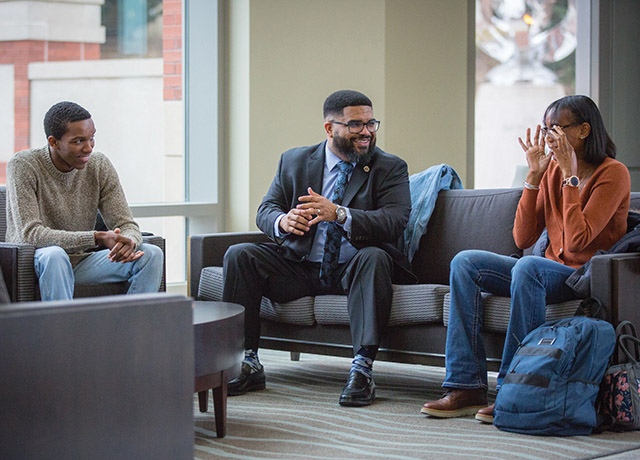 Dr. Christopher Whitt speaks with two people on campus.