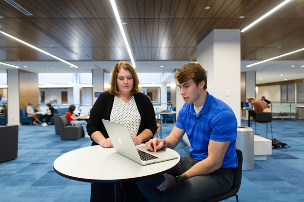 Heider College of Business interior, student and professor.