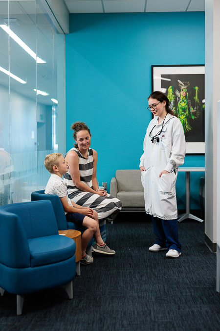 A dental student speaks with a pediatric patient and his mother in the School of Dentistry's pediatric clinic.