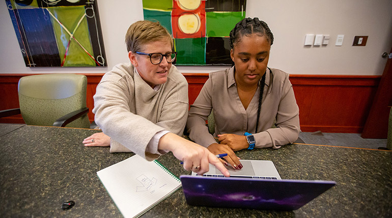 Joy Suder and Sidnea Brown look at a laptop screen.