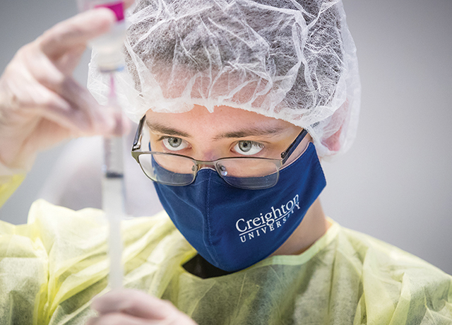 Student wearing PPE works in the pharmacy lab