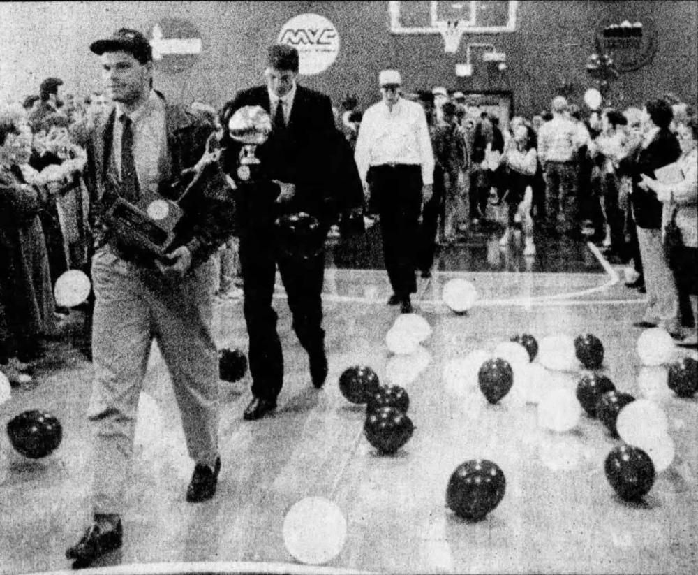 Basketball players walk past balloons and fans
