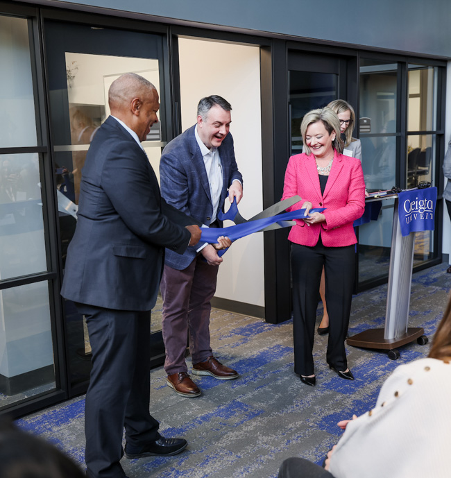 Scott Shipman cuts the ribbon opening the Child Safety Center, with some assistance from Mayor Ewing and Chanda Chacón.