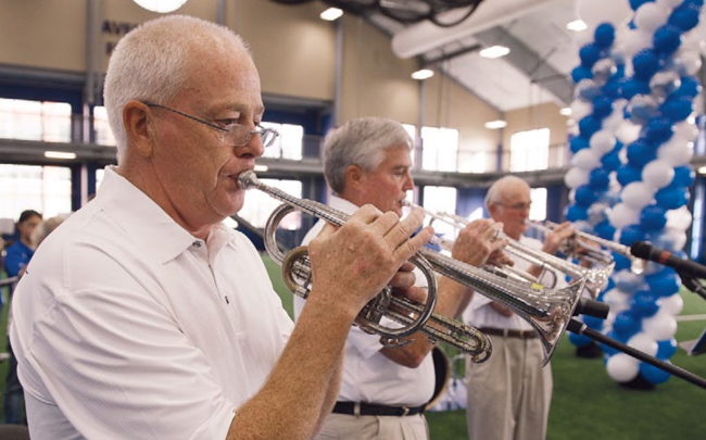 From left: Bruce Rasmussen and John and Bill Scott play the Creighton fight song at the opening of the Rasmussen Center.