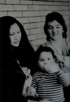 A mother and a child sit next to a student