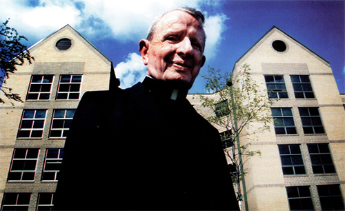 Fr. McGloin in front of McGloin Hall