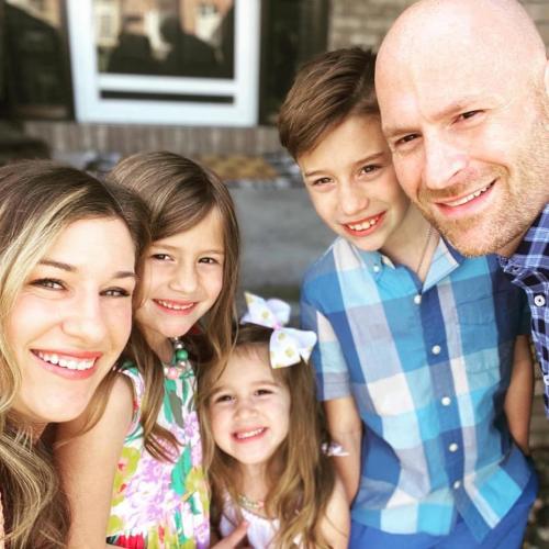 A family of four poses together for a selfie photo